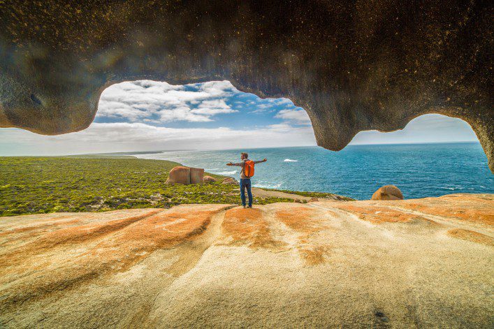 Cheerful young man arms outstretched at The Remarkable rocks-Australia