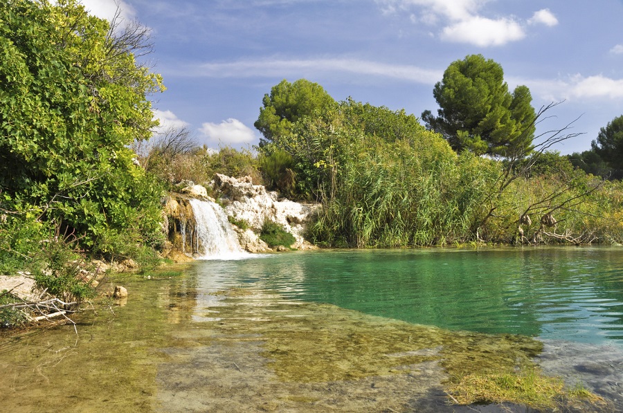 Ein Wasserfall führt Wasser in einen See mit klarem Wasser.