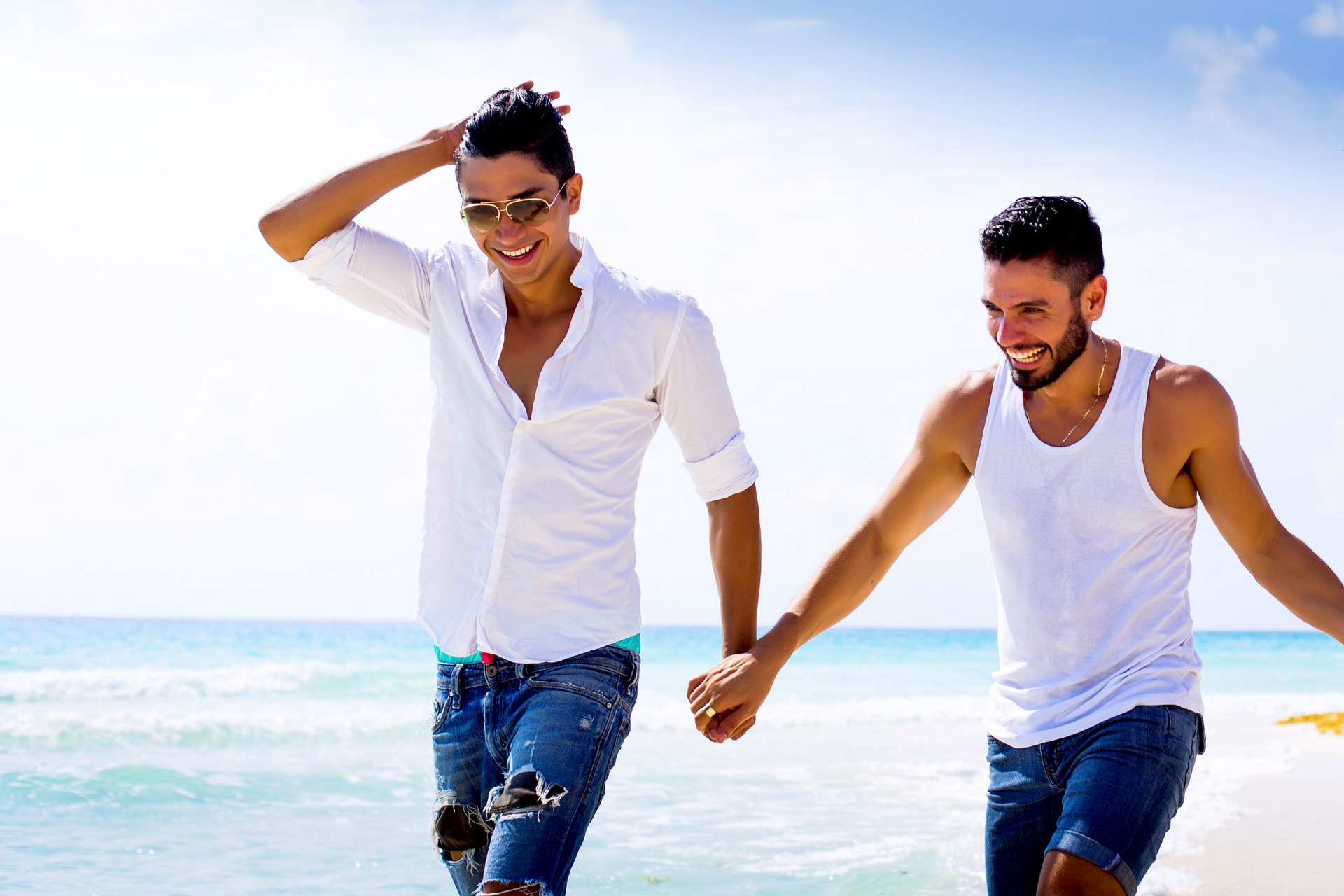 Zwei Männer laufen händchenhaltend den Strand entlang 