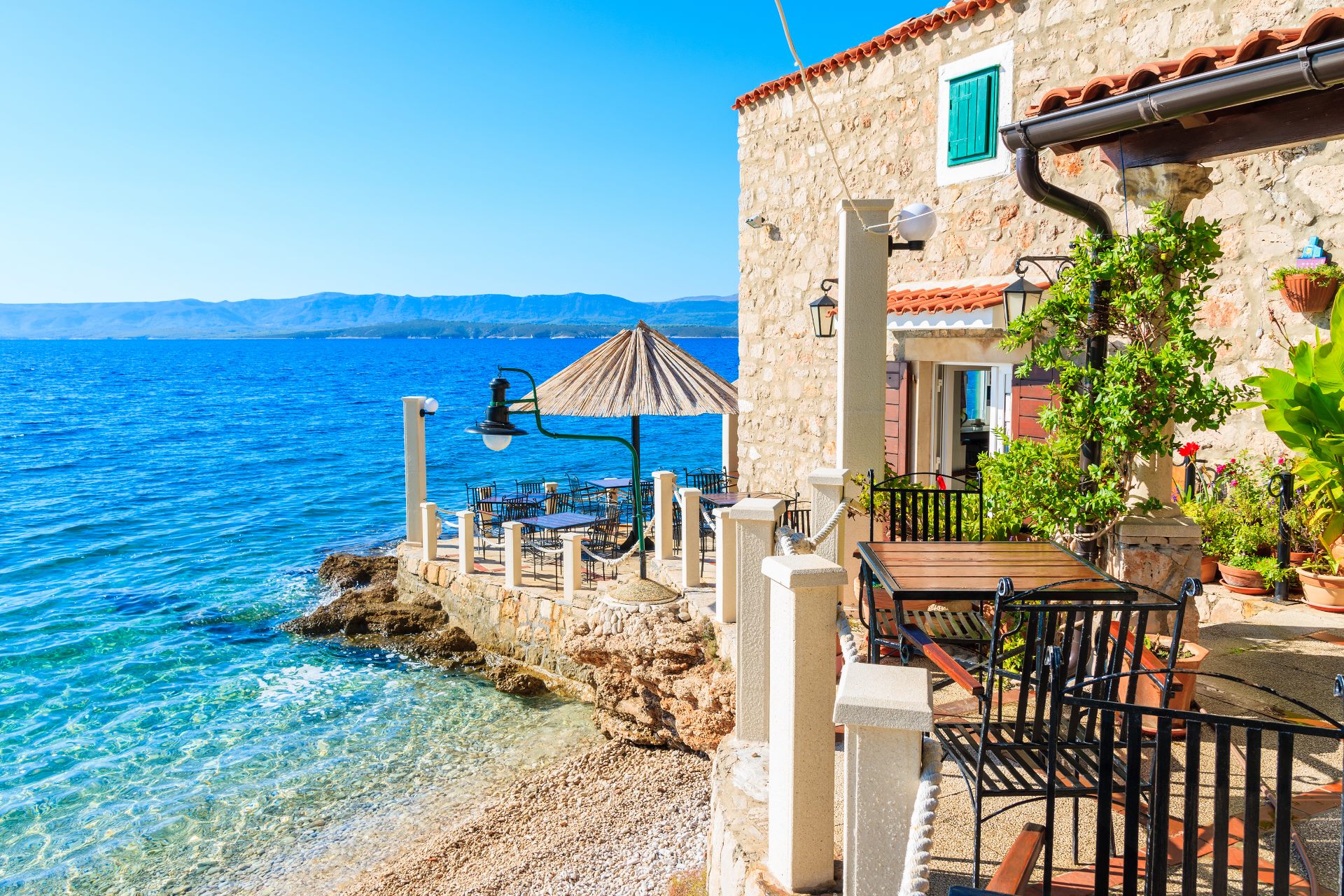 Terrasse mit Stühlen am Meer auf der Insel Brac in Kroatien