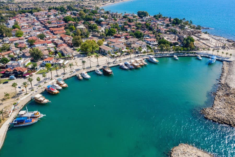 Ein malerischer Hafen in Side, Türkei, mit Booten, umgeben von roten Dächern und Stränden, konkurrierend mit Alanyas Schönheit.